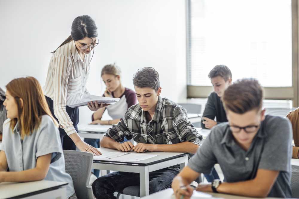 Group of college students doing exam at classroom