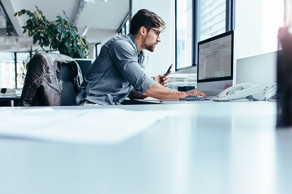 Young man sitting in office and working on desktop pc