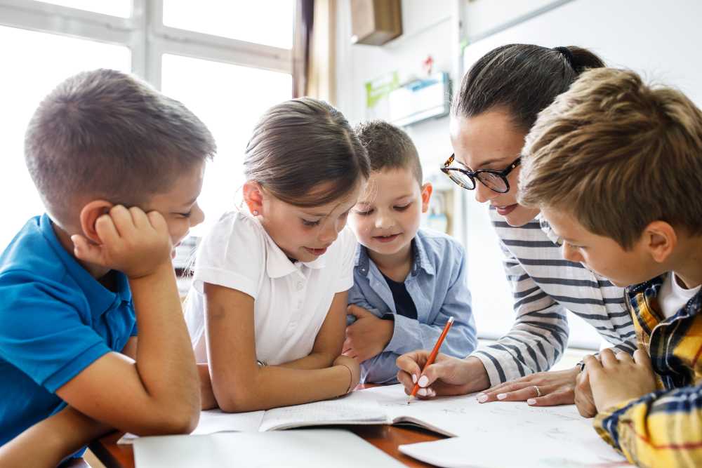 Female teacher helps school kids to finish their lesson