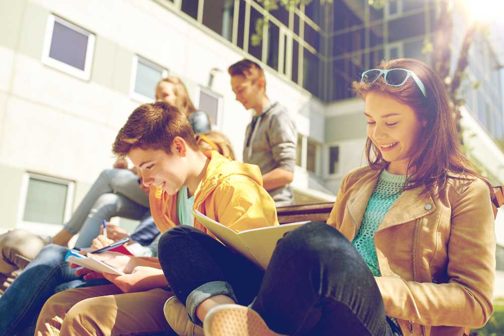 Group of happy teenage students with notebooks